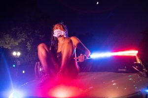 A protester sits and yells on the hood of a Metropolitan Police Department Car in Washington, D.C. on July 25, 2020. Photo - Kaylee Greenlee / Daily Caller News Foundation)