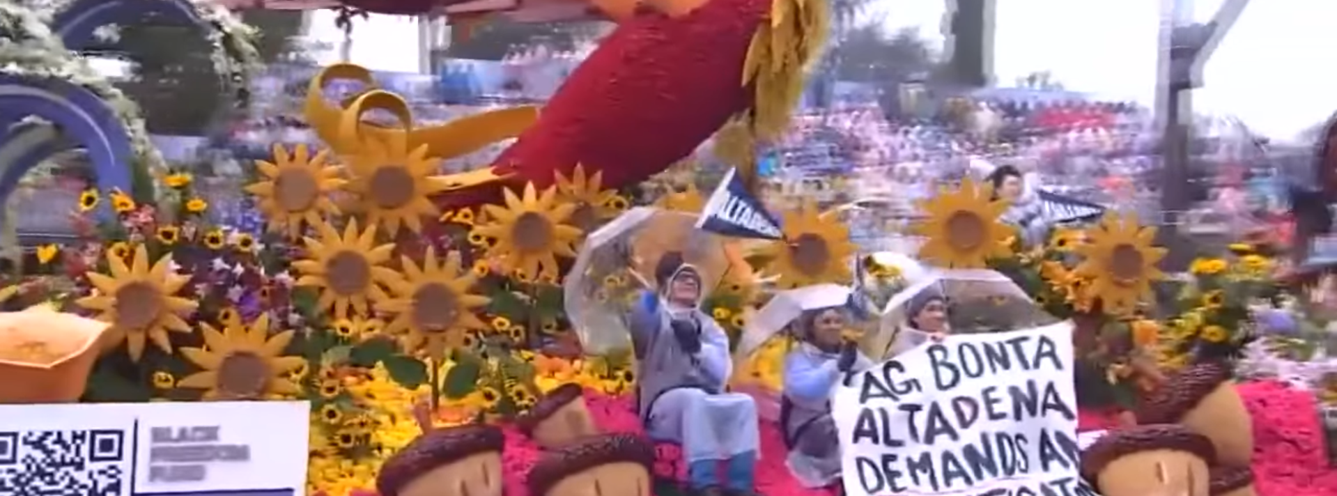 Raincoat-Clad Bootlicker Pulls Down Rose Parade Sign Demanding Accountability For Deadly Wildfires
